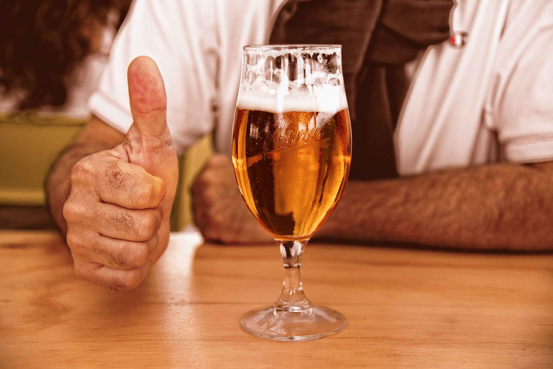 Man giving a thumbs-up beside a craft beer