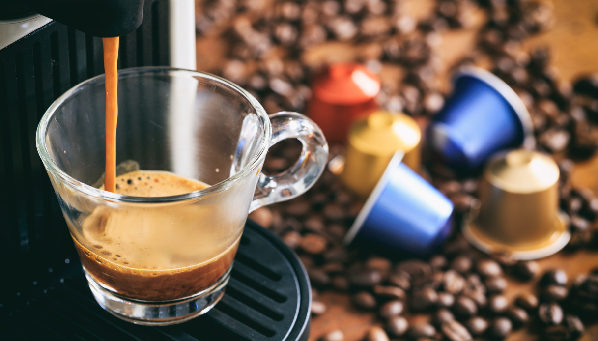 Espresso pouring beside assorted coffee capsules
