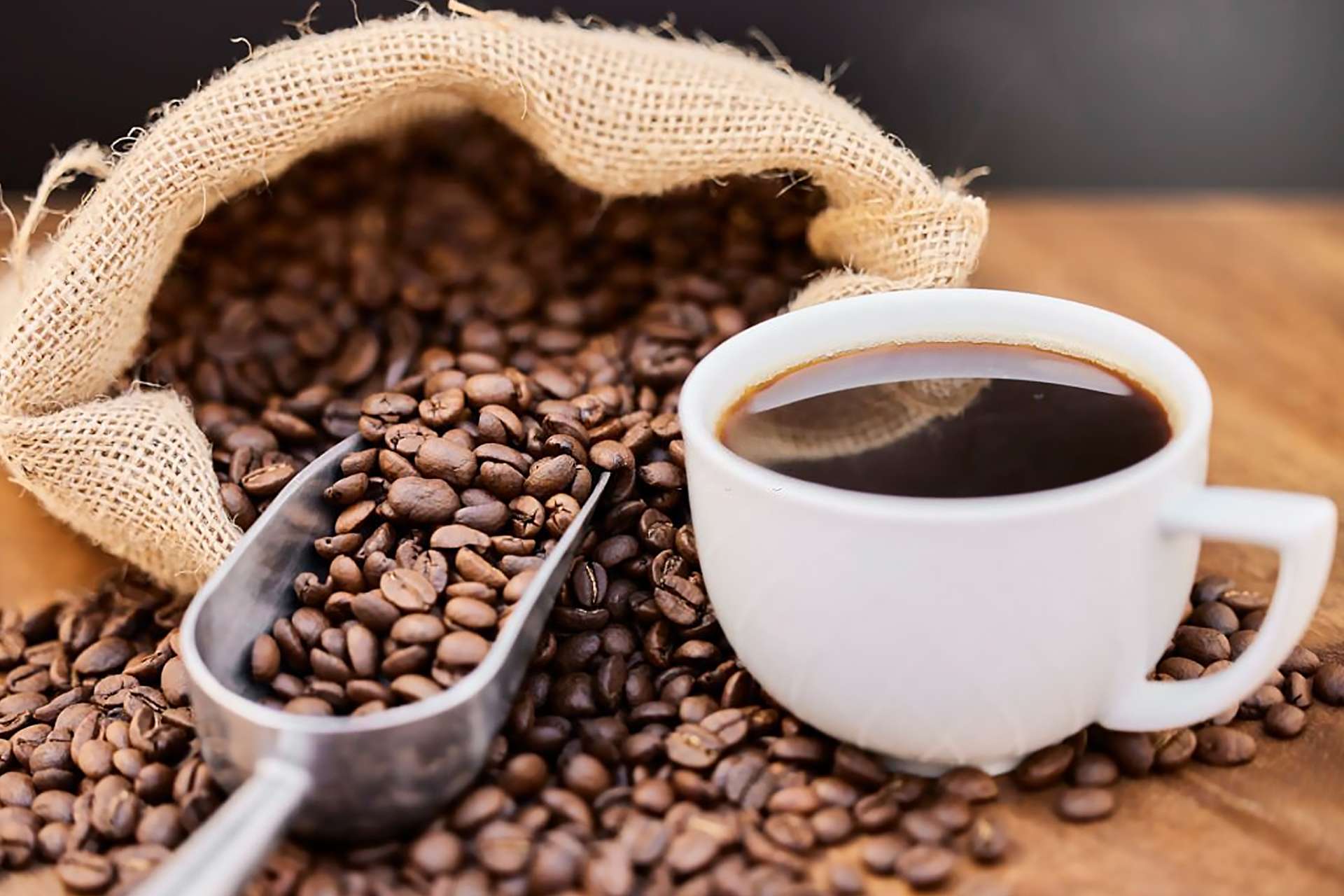 Cup of coffee beside roasted coffee beans